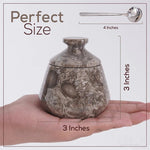 Small stone-patterned urn held in a hand with measurements shown