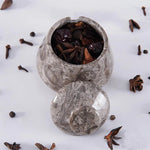 Decorative stone container filled with star anise on a white background