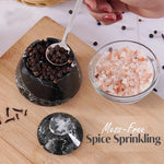 Black marble spice container with a spoon, salt, and pepper on a wooden surface.