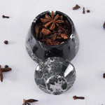 Black marble container with star anise and cloves on a white background