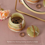 Decorative jewelry box with marble pattern on a pink surface with flowers and a ring.