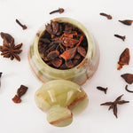 Decorative container with dried spices on a white background