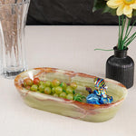 A marble dough bowl on a table, filled with various candies and a small vase with pink flowers in the background.