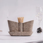 A beige marble onyx salt and pepper shaker set with a tray, displayed on a table with a soft background.