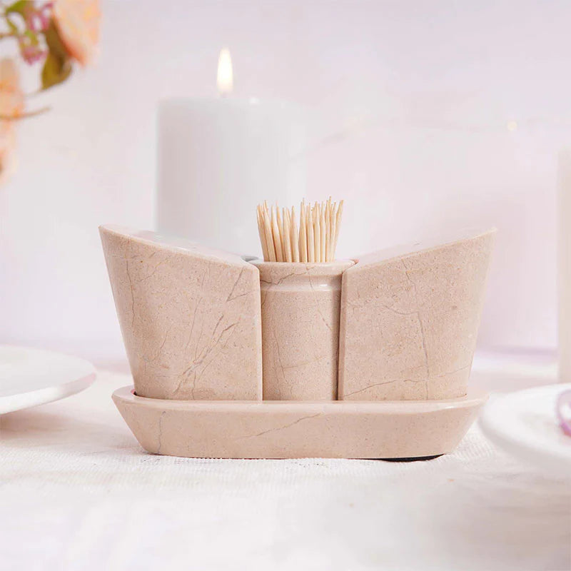 A beige marble onyx salt and pepper shaker set with a tray, displayed on a table with a soft background.