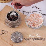Hand using a spoon to sprinkle spices from a container and a bowl on a wooden surface.