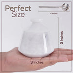 White ceramic teapot held in a hand with measurements shown