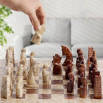 Hand placing a stone chess piece on a marble chessboard with a blurred indoor background