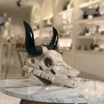 Decorative skull with black horns on a marble surface in an indoor setting
