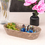 A marble dough bowl on a table, filled with various candies and a small vase with pink flowers in the background.