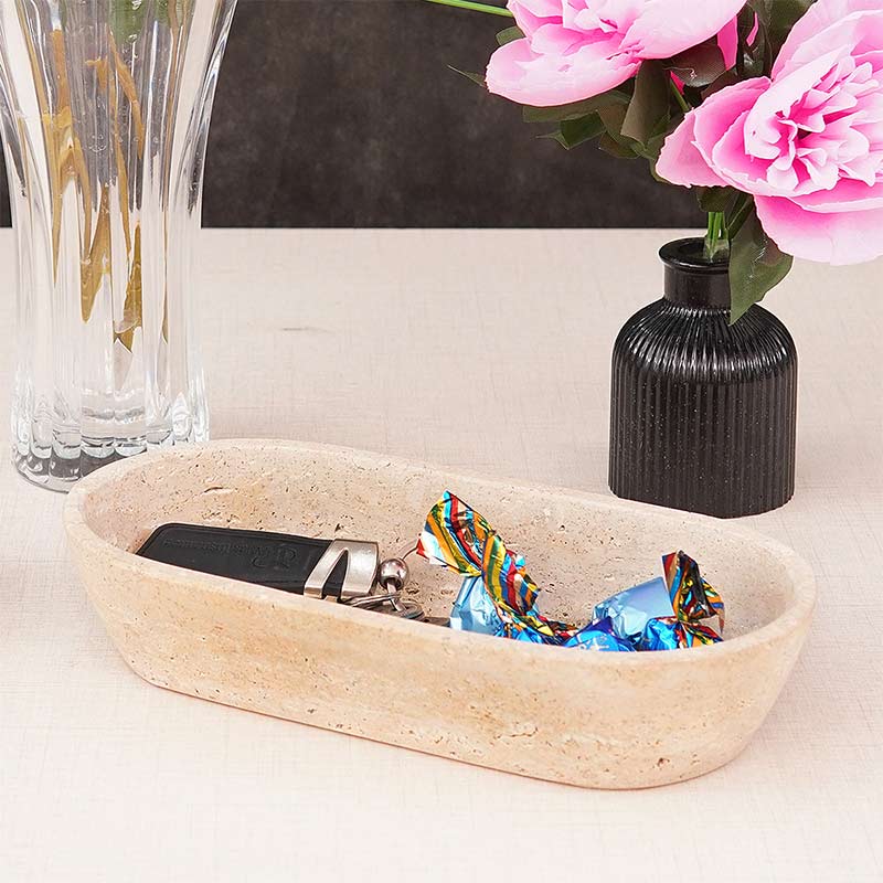 A marble dough bowl on a table, filled with various candies and a small vase with pink flowers in the background.